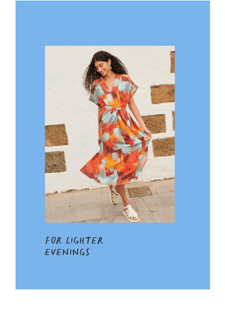 woman in printed linen dress dancing in front of white washed wall